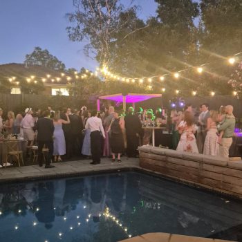 Guests enjoying a lively poolside night party with lights and music